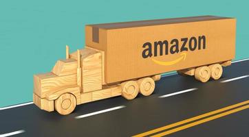 Wooden toy truck, carrying a large cardboard box with Amazon logo, moves fast on the road. photo