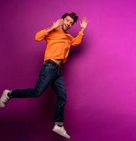 Happy man jumps against a purple background photo