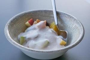 Fresco frutas mezclado con yogur en un cuenco en mesa foto