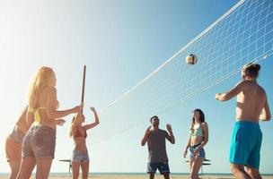 Group of friends playing at beach volley at the beach photo