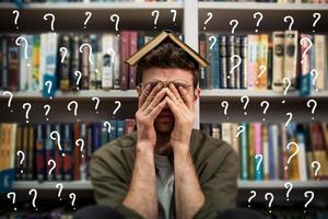 Tired university student has difficulty to study. Full of question mark. Concept of stress and difficulty photo