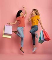 Two girls are happy after shopping. Joyful expression. Shop concept. Pink background photo