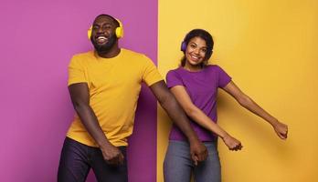 Pareja con auriculares escucha a música y danza con energía en Violeta y amarillo antecedentes foto