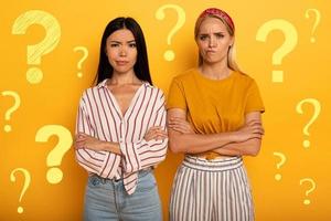 Two girl with troubled expression are diffident about something. Yellow background photo