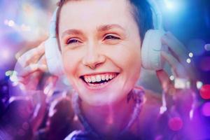 niña escucha a música con blanco auriculares sonriente. disco antecedentes foto