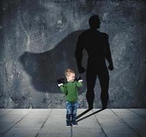 joven niño con su sombra de súper héroe en el pared. foto