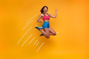 Sport woman jumps on a yellow background. Happy and joyful expression. photo