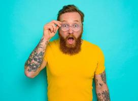 Man with yellow t-shirt and beard is shocked about something photo