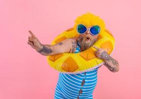 Fat amazed man with wig in head is ready to swim with a donut lifesaver photo