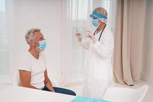 Doctor with mask and syringe is ready to administer the vaccine against covid-19 photo