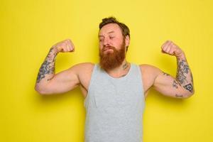 Man with beard and tattoos shows with pride his muscle photo