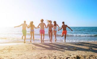 Group of friends run in the sea. Concept of summertime photo