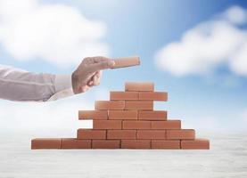 Businessman puts a brick to build a wall. Concept of new business, partnership, integration and startup photo