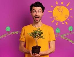 Happy boy holds a small tree ready to be planted over a light color. concept of forestation, ecology and conservation photo