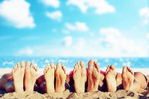 Group of friends having fun on the beach with their foots. Concept of summertime photo