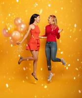 Girls ready for a party with balloons. Joyful an happiness expression. Yellow background photo