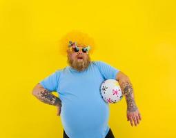 Fat annoyed man with wig in head and sunglasses have fun with a ball photo