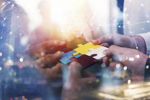Business people join puzzle pieces in office. Concept of teamwork and partnership. double exposure with internet network effects photo
