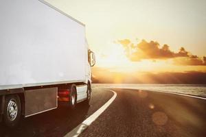 White truck moving on the road in a natural landscape at sunset photo