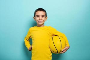 Child ready to play at basketball. Cyan background photo