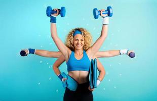 Multitasking girl at the gym. Concept of fatigue and stress. Cyan background photo