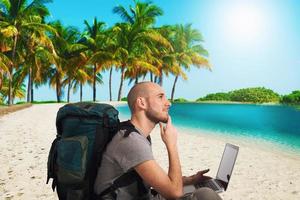explorador planes un nuevo viaje a un tropical playa con su ordenador portátil foto