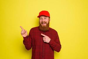 Happy delivery man with hat and beard indicates something photo