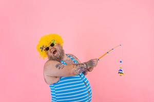 Fat happy man with beard and sunglasses have fun with the fishing pole photo