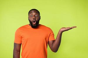 Surprised black man holds something in hand. Yellow background photo