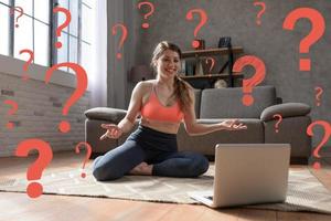 Young woman follows gym exercises with a laptop but sha has some questions photo