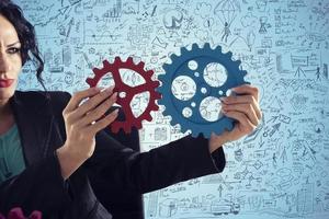 Businesswoman tries to connect gears pieces. Concept of Teamwork, partnership and integration photo