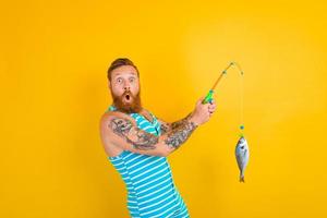 man with beard and swimsuit caught a fish photo