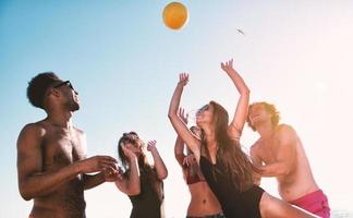 Group of friends playing at beach volley at the beach photo