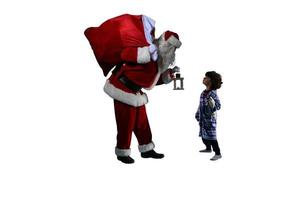 Papa Noel claus es dando un presente para Navidad a un pequeño chico foto