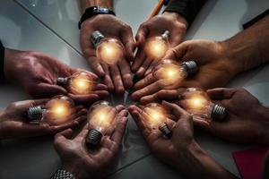 Teamwork and brainstorming concept with businessmen that share an idea with a lamp. Concept of startup photo