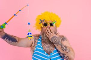 Fat amazed man with beard and sunglasses have fun with the fishing pole photo