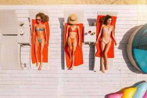 grupo de amigos en traje de baño bebida un cóctel en un nadando piscina foto