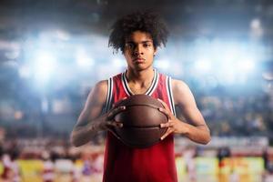 baloncesto jugador sostiene el pelota en el cesta en el estadio lleno de público. foto