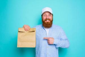 Deliveryman with happy expression is ready to deliver a food package photo