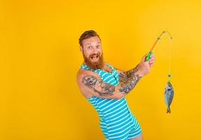 man with beard and swimsuit caught a fish photo