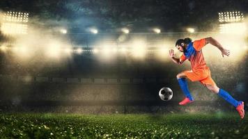 Soccer player in orange and blue uniform sprinting fast with the ball at the stadium photo