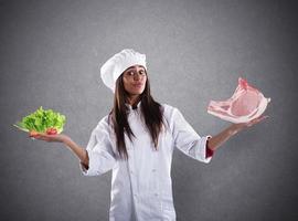 Chef undecided between fresh salad or meat steak. concept of vegetarian photo