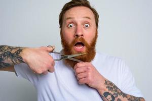 Amazed man with scissors doees not want to cut the beard photo