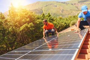 Workers assemble energy system with solar panel for electricity and hot water photo