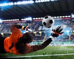 Goalkeeper catches the ball in the stadium during a football game. photo