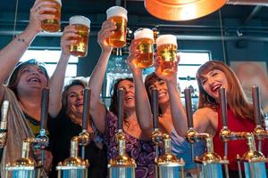 group of mature women is drinking beer in a pub in front of a beer tap photo