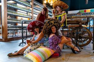 grupo de atractivo mujer vistiendo mexicano sombreros teniendo un bueno hora Bebiendo cerveza foto