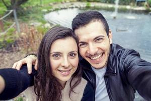 bonito Pareja novios toma un selfie relajante en el parque al aire libre foto