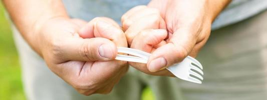 Male hand breaks plastic disposable fork photo