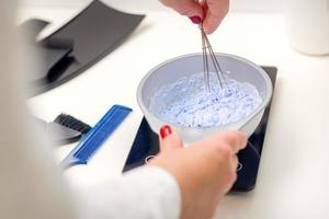 Hairdresser is mixing dye in white bowl photo